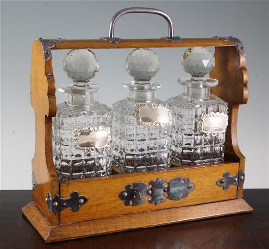 An Edwardian plated mounted oak three bottle tantalus, with three later silver spirit labels, tantalus 12.75in over handle.